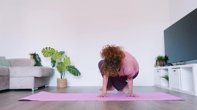 Flexible woman performing side crow pose at home
