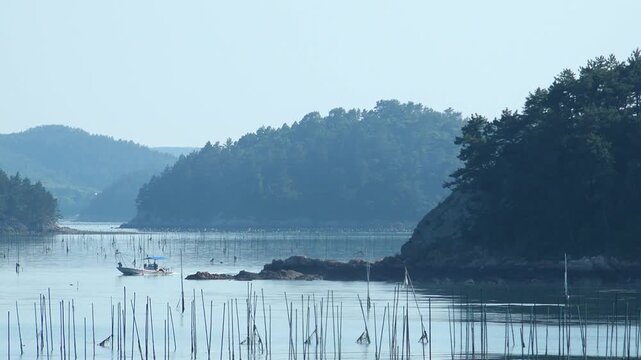 Scenic view of a peaceful Korean southern sea fishing village with local fisherman boats, mudflats, and islands in Namhae / 한국 남해바다 어촌 마을 풍경, 어민들의 고기잡이 배와 평화로운 섬, 갯벌 해안가 풍경 영상