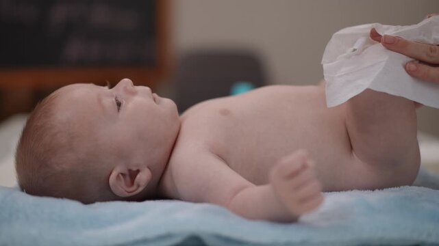 Mother changing the diaper of her newborn baby son lying on a changing table