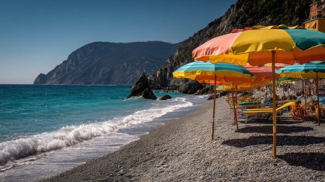 Colorful beach umbrellas lined along the sandy shore of Monterosso al Mare on the Italian Riviera with turquoise Mediterranean Sea, scenic coastal landscape and popular summer vacation destination