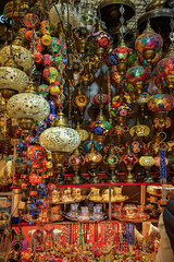 Fototapeta premium A crowded and vibrant market display filled with traditional Turkish mosaic lamps, hanging glass lanterns, ceramic ornaments, and decorative tea glasses at a souvenir shop or oriental bazaar.