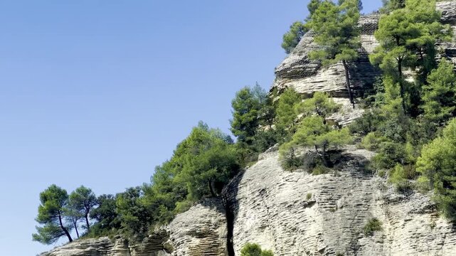 Eroded pale limestone cliff with stratified rock layers crowned