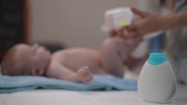 Mother changing her newborn baby's diaper at home