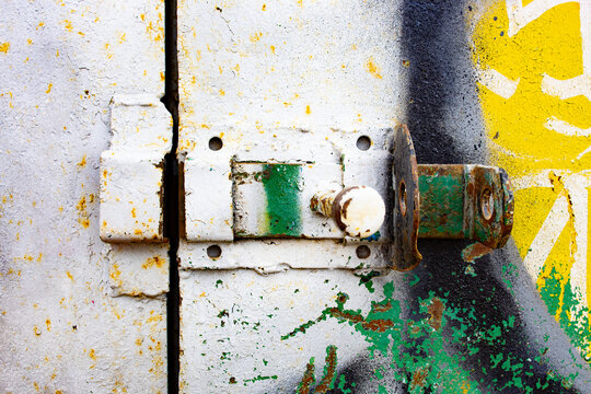 Rusty barrel bolt lock on weathered door with paint layers