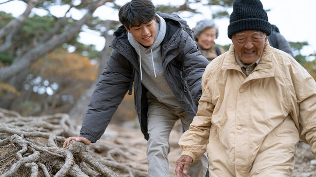 Korean family hiking trail weekend, three-generation group on forested mountain path, teenage son helping elderly grandfather over root, autumn foliage, multigenerational outdoor