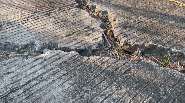 Broken textured cement road with deep structural crack
