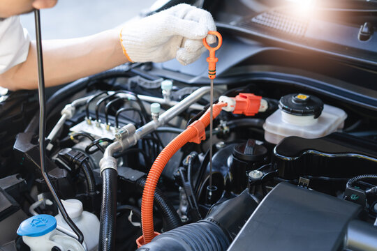 Auto technician performing routine maintenance check on a hybrid car engine.