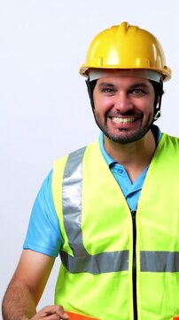Portrait of a Joyful and Confident Indian Bearded Civil Engineer in Fluorescent Safety Jacket and Yellow Hard Hat Celebrating Success standing against White background