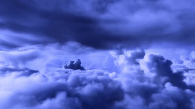 Elevated cloudscape with billowing cumulus towers beneath dark stratocumulus ceiling in deep blue twilight light, showing layered texture, broad horizon, and moody atmospheric depth above calm