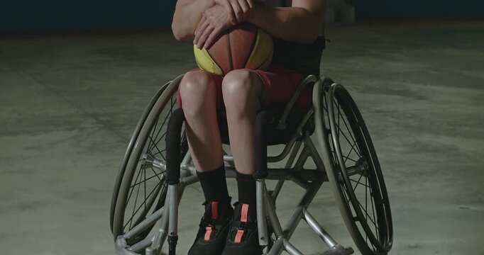 Portrait of an adaptive basketball athlete holding a ball inside an indoor sports facility, emphasizing determination, disability inclusion, resilience, 