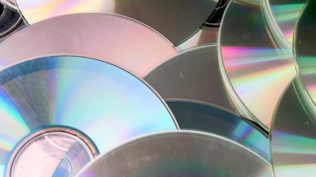 Rotating CD discs in close-up, metallic texture and circular motion forming dynamic and minimal scene. Perfect for digital media content, nostalgia concepts, abstract background visuals