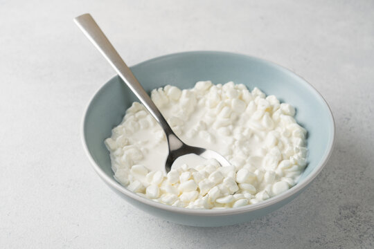 Fresh high protein cottage cheese bowl with creamy texture served in blue ceramic bowl on light background with copy space