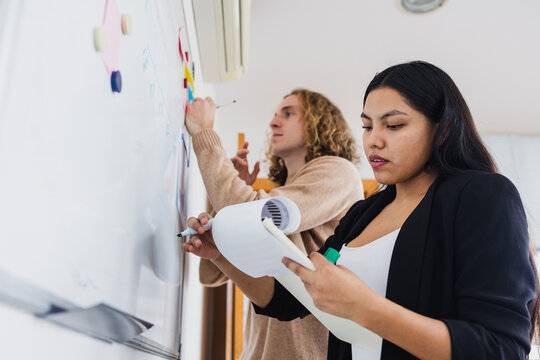 young latina Businesswoman writing on whiteboard in office in Latin America, Hispanic business people at workplace