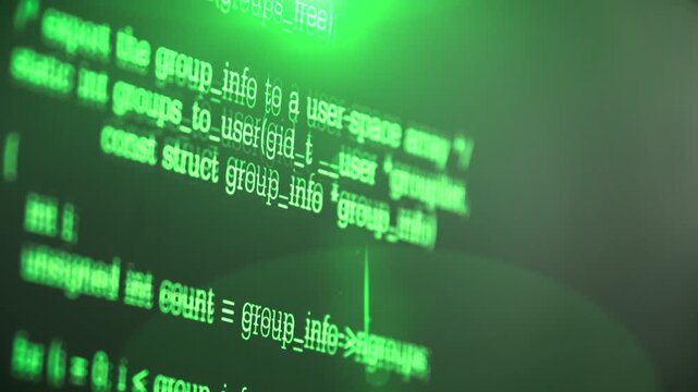 close up shot of computer monitor display showing green programming source code lines on dark screen.