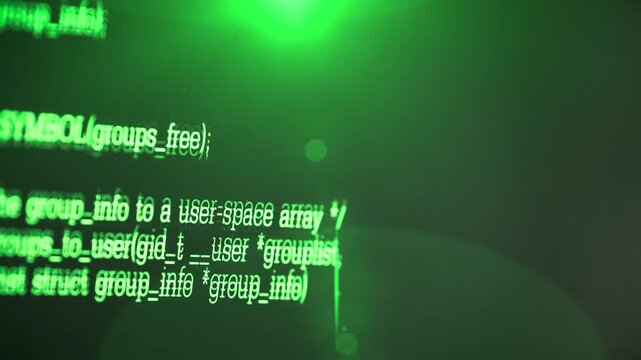 close up shot of computer monitor display showing green programming source code lines on dark screen.