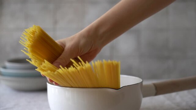 Video of spaghetti pasta during cooking process. Close-up cinematic view of pasta strands moving in pan, creating an authentic Italian comfort food preparation scene. Warm culinary atmosphere, homemad