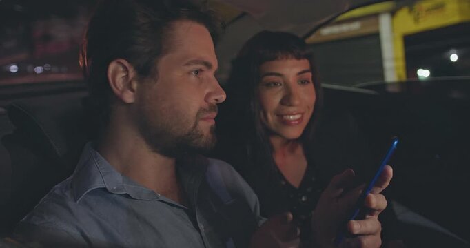 Business colleagues discussing information on a smartphone while traveling in the back seat of a