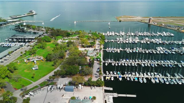 A drone flies above a marina where dozens of boats are docked in neat rows.