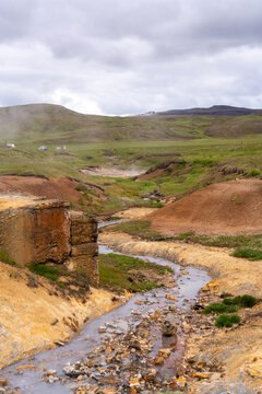 Steaming geothermal creek in a valley of red and yellow mineral earth, Selt&uacute;n, Iceland