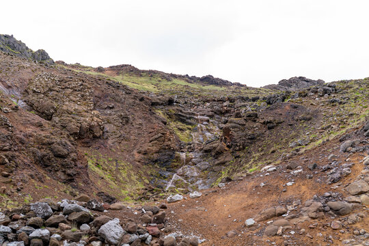 Small stream trickling down a rugged moss-covered volcanic ravine, Iceland