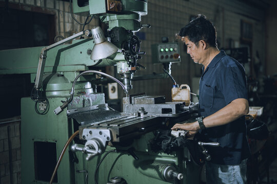 Skilled Machinist Operating Drill Press Machine in Small Community Metalworking Workshop