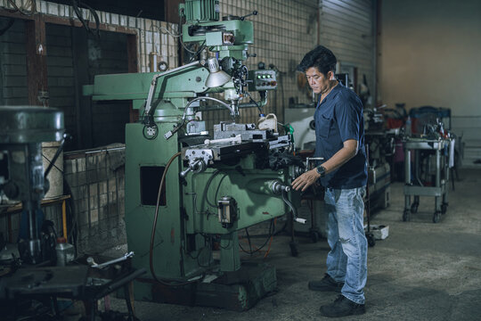 Skilled Machinist Operating Drill Press Machine in Small Community Metalworking Workshop