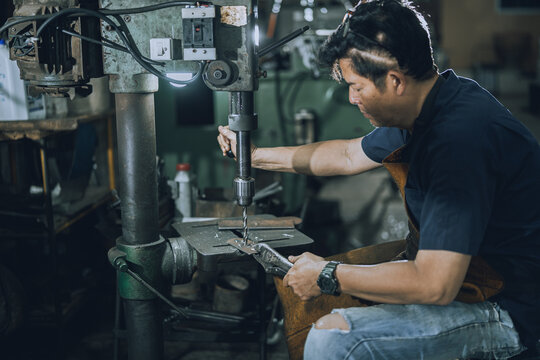 Skilled Machinist Operating Drill Press Machine in Small Community Metalworking Workshop