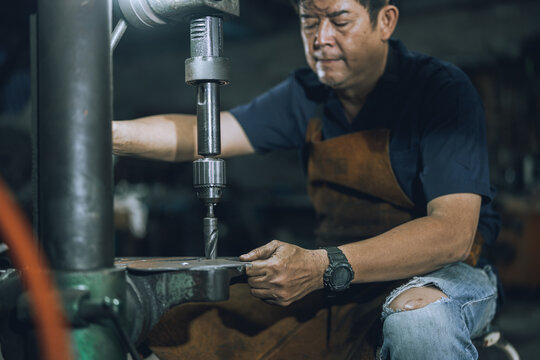 Skilled Machinist Operating Drill Press Machine in Small Community Metalworking Workshop