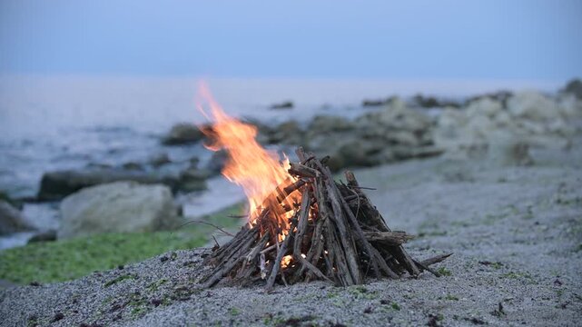 Beach bonfire with sound of ocean waves and cargo ship on the horizon at dusk