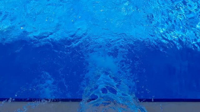 Top view of a spa pool hydromassage jet with flowing water and bubbles.