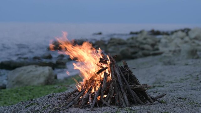 Beach bonfire with sound of ocean waves and cargo ship on the horizon at dusk