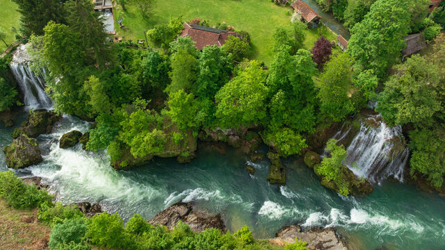 Drone captures beautiful canyon village of Rastoke near Slunj. Rapid rivers, waterfalls, and traditional wooden watermills integrate perfectly with lush green nature in famous Croatian landmark.