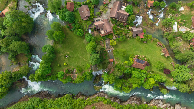 Drone captures beautiful canyon village of Rastoke near Slunj. Rapid rivers, waterfalls, and traditional wooden watermills integrate perfectly with lush green nature in famous Croatian landmark.