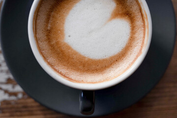 Fototapeta premium Minimalist close-up of a cup of coffee photographed in soft natural light with visible film grain, warm tones and an analog-inspired aesthetic.