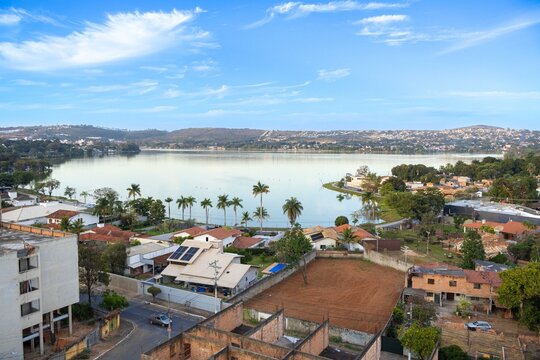 Panoramic view of Central Lagoon in Lagoa Santa, Minas Gerais, Brazil, featuring the lakeshore, residential neighborhood, palm trees, vegetation and blue sky. Urban landscape in the metropolitan regio