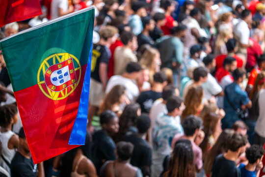 Crowd gathers in Portugal with a flag waving during a public event, showing unity and cultural pride