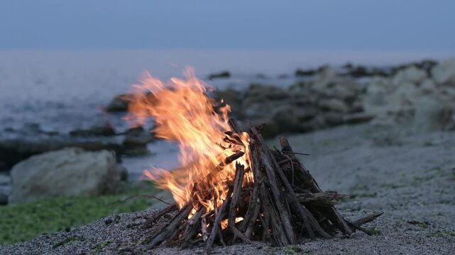 Bonfire burning on a rocky sea beach at dusk