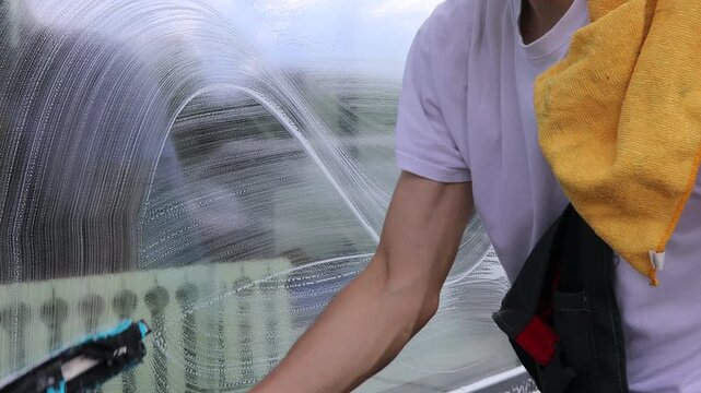 A professional cleaning service worker washes the windows with special foam and cleans them.	