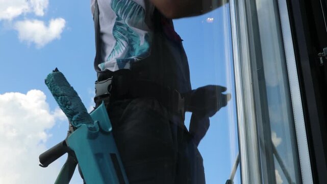 A professional cleaning service worker washes the windows with special foam and cleans them.	