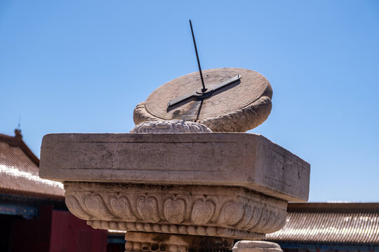 Stone sundial at Supreme Harmony, Forbidden City, Beijing, China, with palace roofs in spring