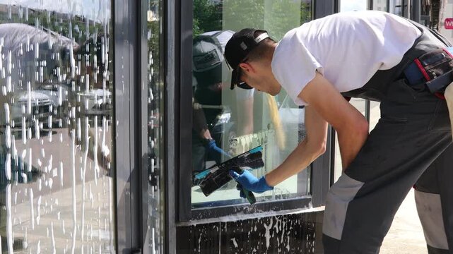 A professional cleaning service worker washes the windows with special foam and cleans them