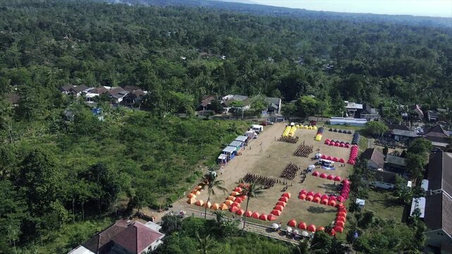 4K aerial view of an organized campsite event in a rural field surrounded by trees.