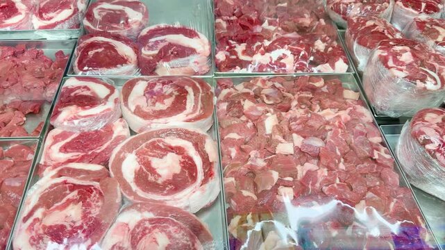 Fresh Meat Display at a Grocery Store Counter.Glass-Topped Refrigerated Meat Counter with Various Cuts of Meat in a Supermarket