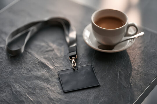 Black lanyard rests beside a coffee cup