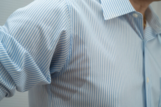 Man with sweat on clothes under armpit when working in office.