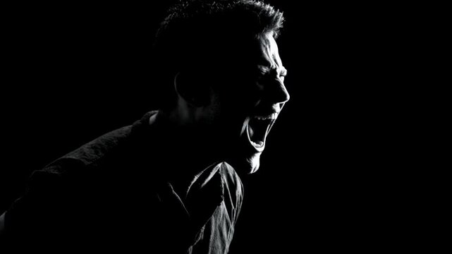 Man screaming in agony. Portrait of male experiencing mental breakdown and emotional pain. Psychological distress, frustration and inner conflict concept. Black