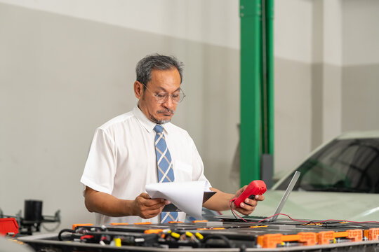 Skilled technician examining electrical systems in a car repair workshop setting