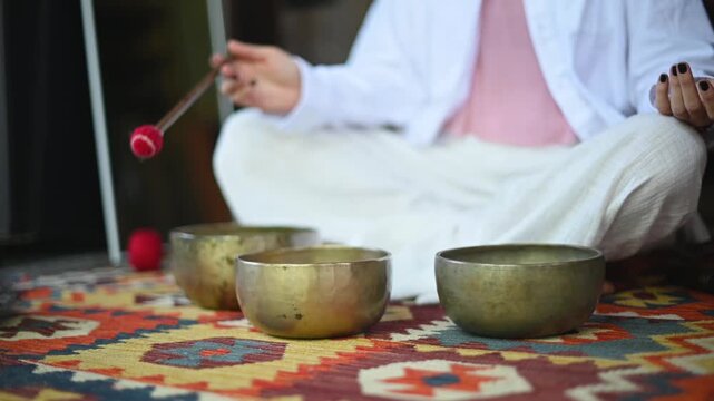 tibetan singing bowls being played on a textile with geometric patterns in a serene setting with metallic bowls and white, red, yellow, and black colors, top-down view.
