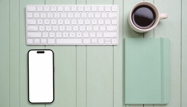 Modern workspace flatlay with white keyboard, smartphone mockup, black coffee, and mint green notebook on light wood, productivity and remote work concept for home office.