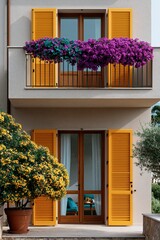 Fototapeta premium Two story mediterranean building with yellow shutters and purple balcony blooms and potted shrubs for exterior wallpaper and architectural background design